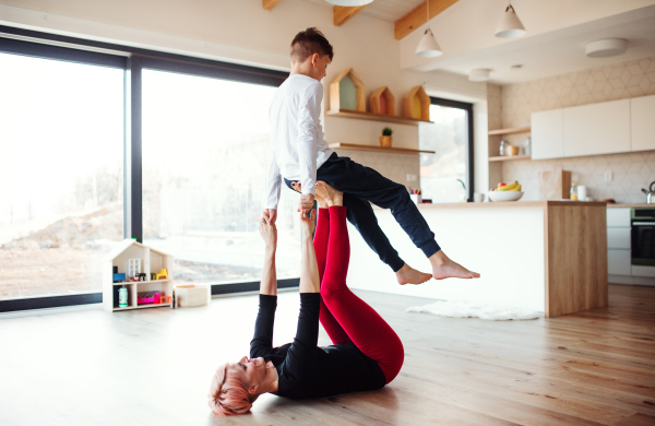 A happy young woman with small son playing on the floor, having fun.