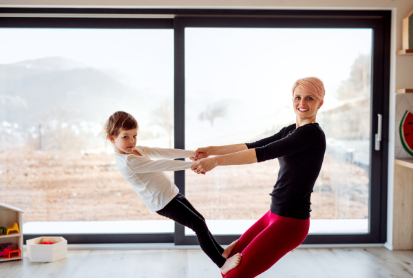 A young cheerful woman with small daughter playing at home, having fun.