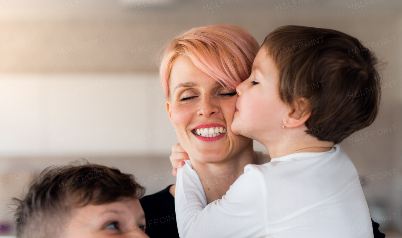 A front view of young woman with two children indoors at home, having fun.