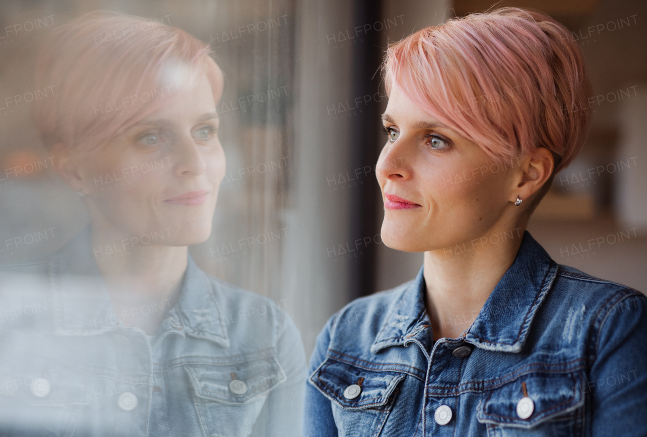 A close-up portrait of young attractive woman standing by window at home. Copy space.