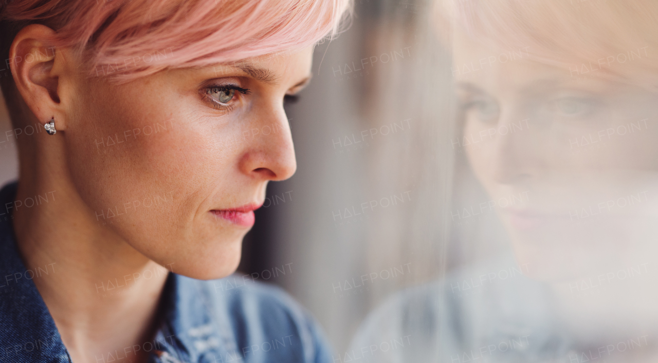 A close-up portrait of young attractive woman standing by window at home. Copy space.