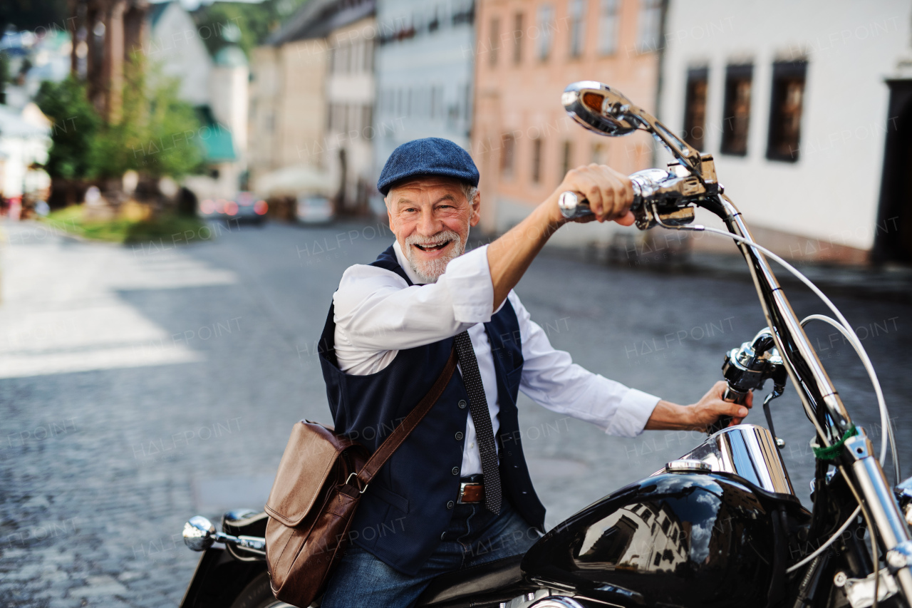 A happy senior businessman with motorbike in town.