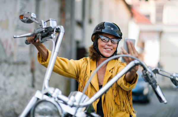 A cheerful senior woman traveller with motorbike in town.