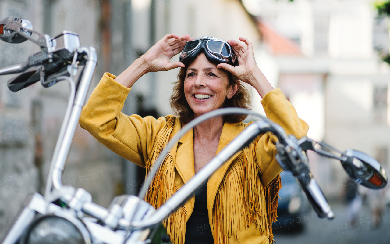 A cheerful senior woman traveller with motorbike in town.