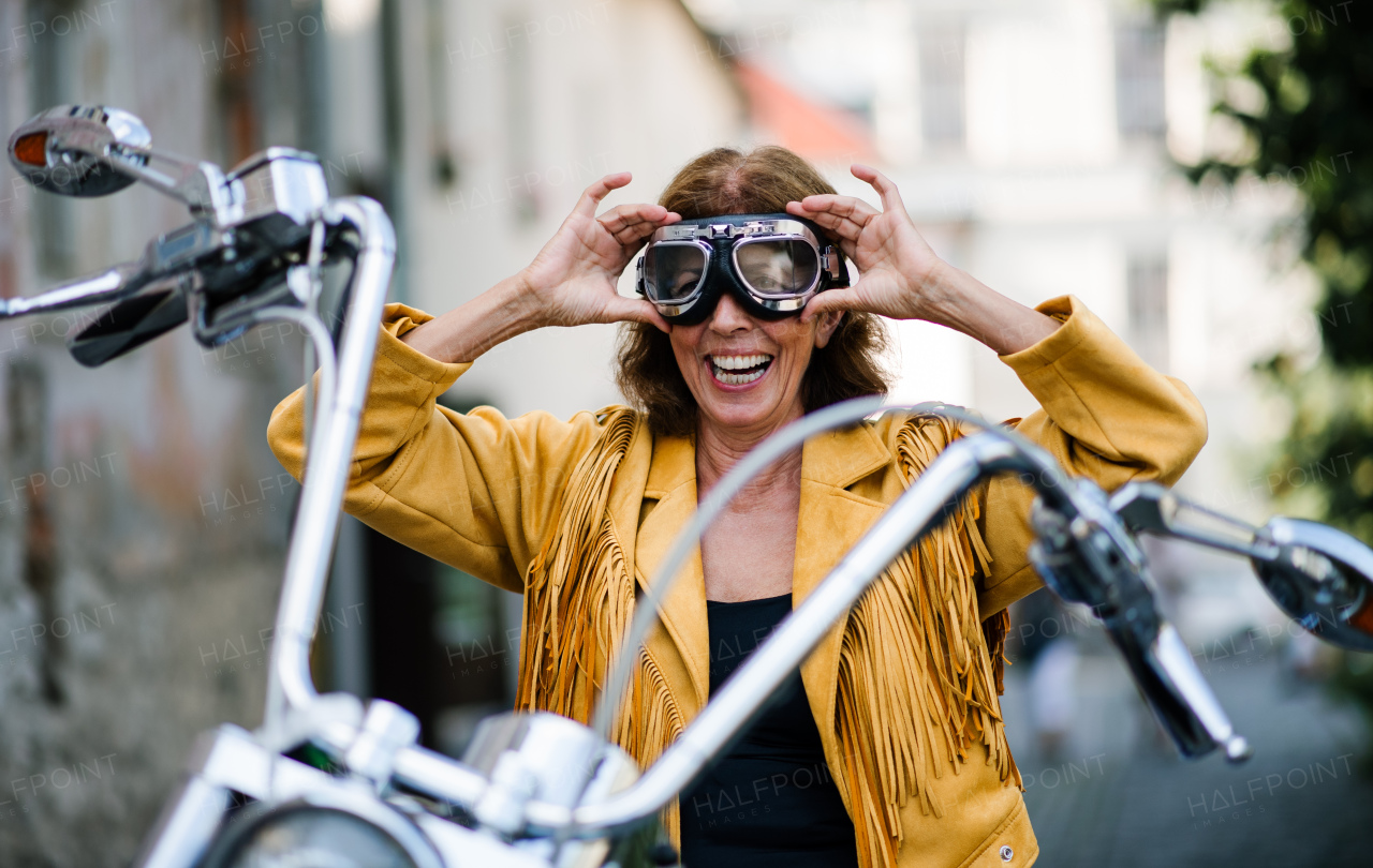 A cheerful senior woman traveller with motorbike in town.