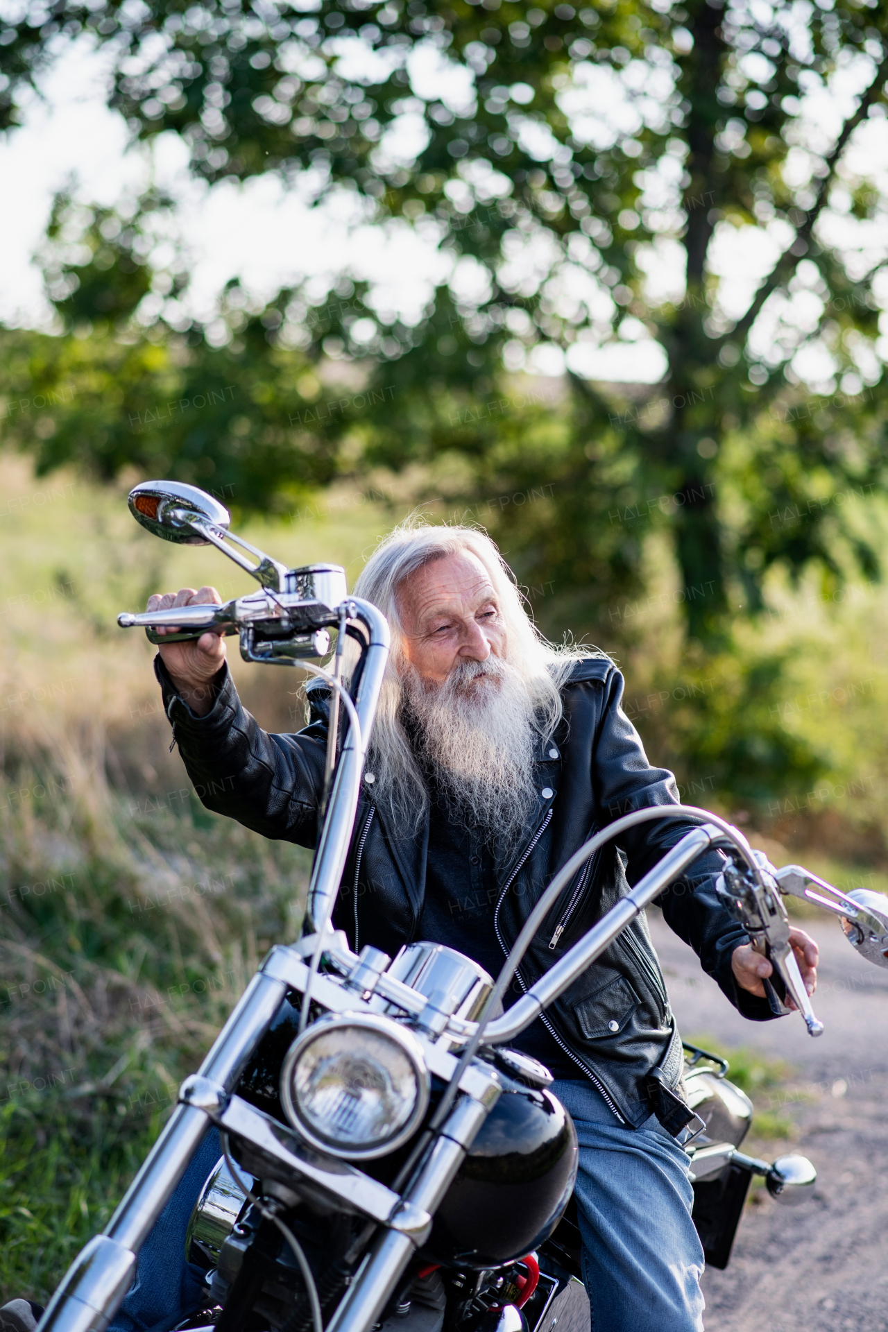 A senior man traveller with motorbike in countryside, resting.