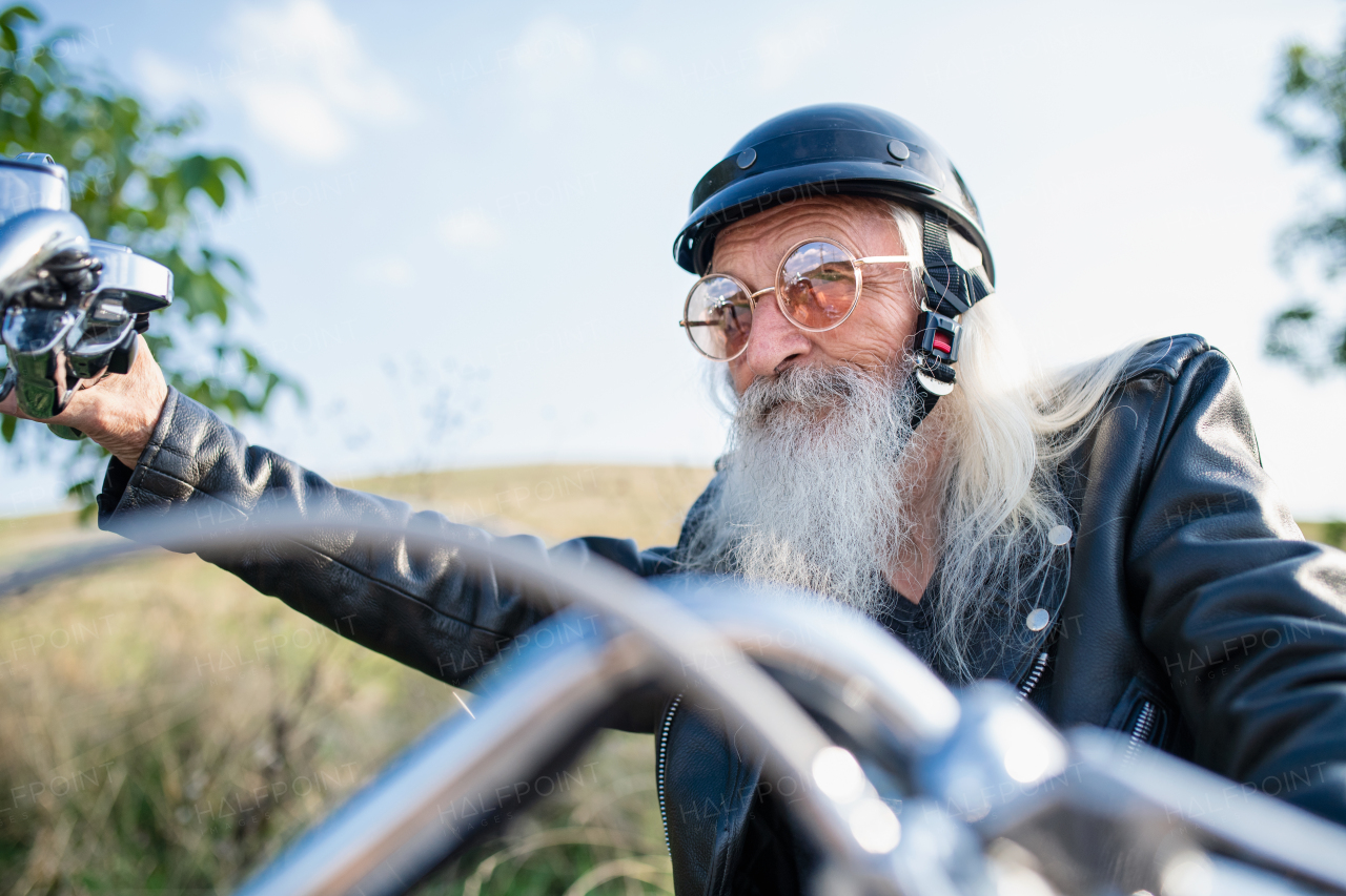 A senior man traveller with motorbike in countryside, resting.