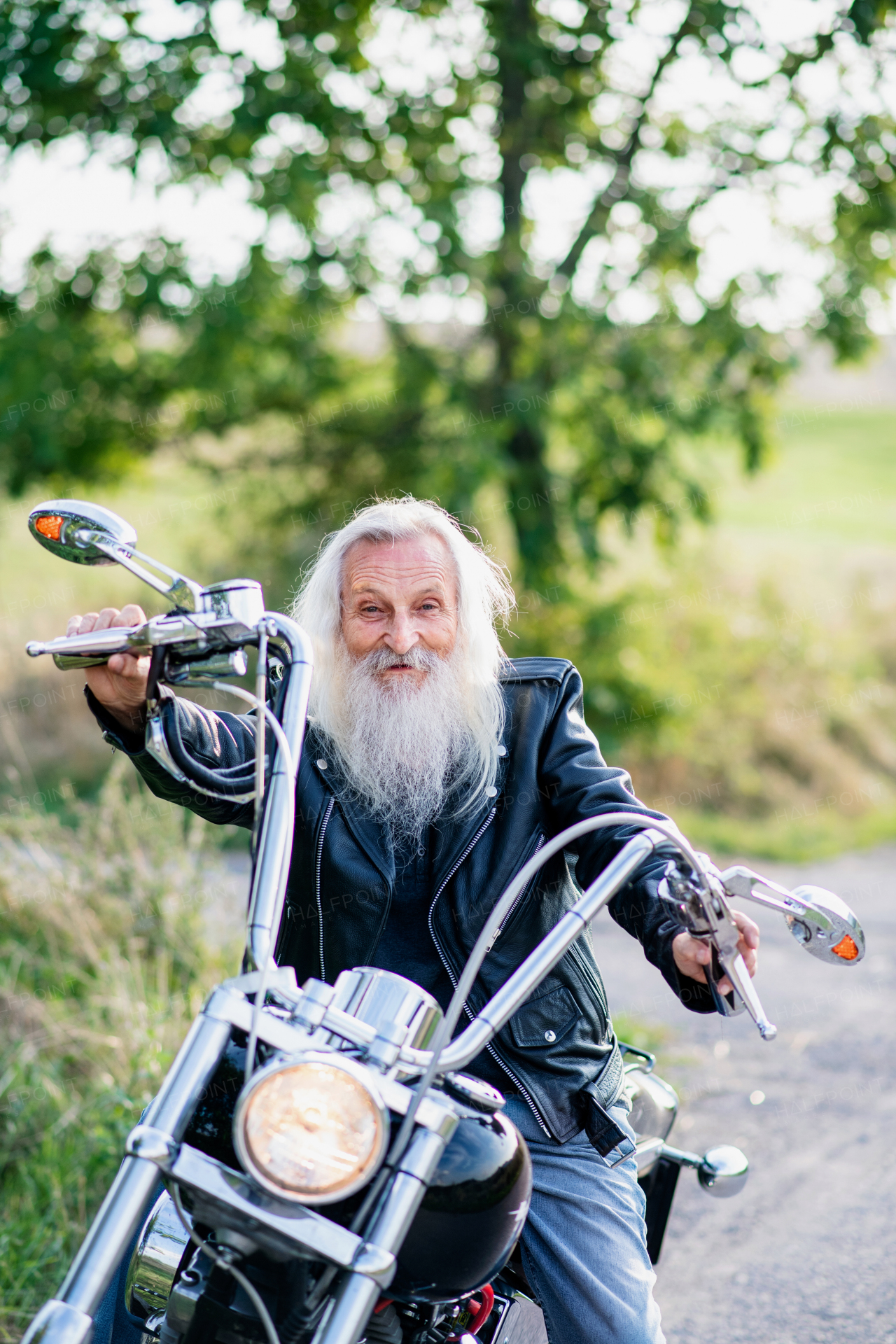 A senior man traveller with motorbike in countryside, resting.