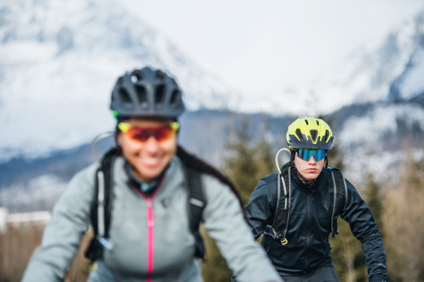 Front view of two mountain bikers riding on road outdoors in winter.