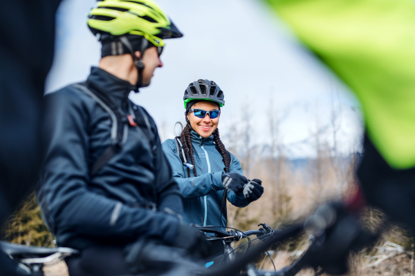 Two mountain bikers standing on road outdoors in winter, resting.