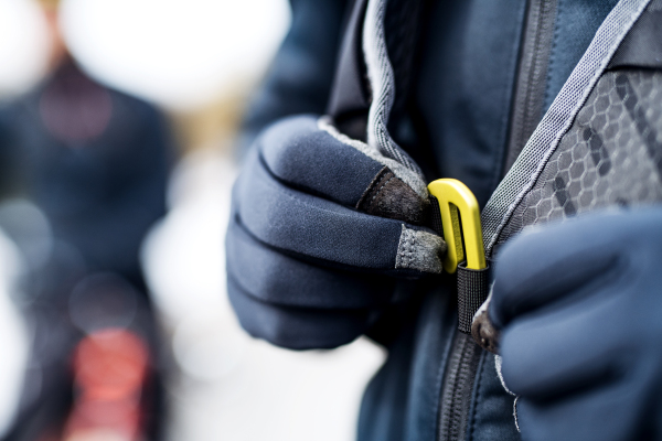 A midsection of mountain biker with backpack on road outdoors in winter