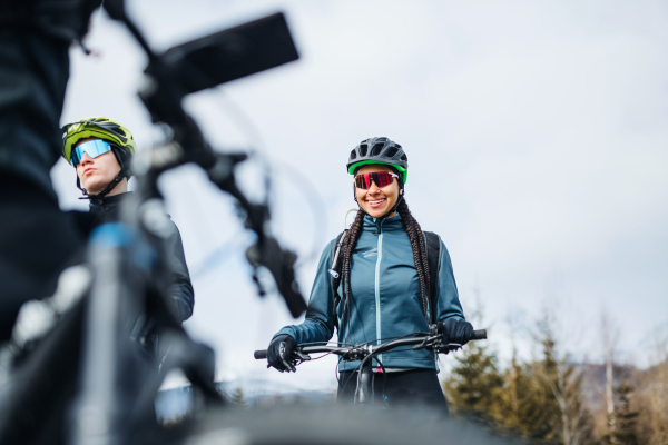 A group of young mountain bikers standing on road outdoors in winter, talking.