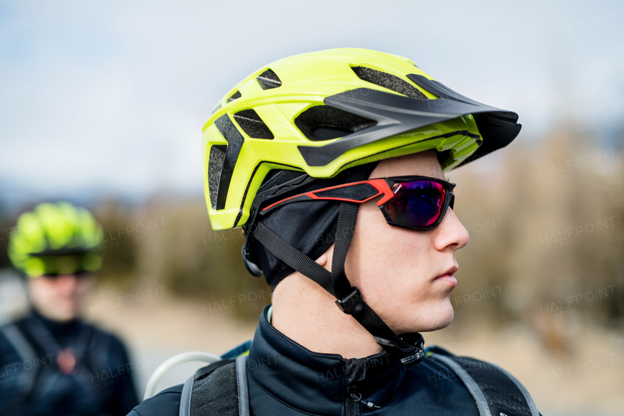 Two mountain bikers standing on road outdoors in winter, close-up.