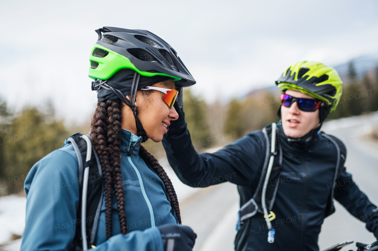 Two mountain bikers riding on road outdoors in winter, talking.