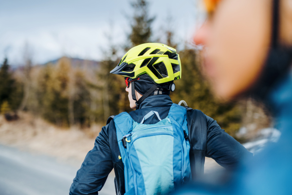 Two mountain bikers standing on road outdoors in winter, resting.