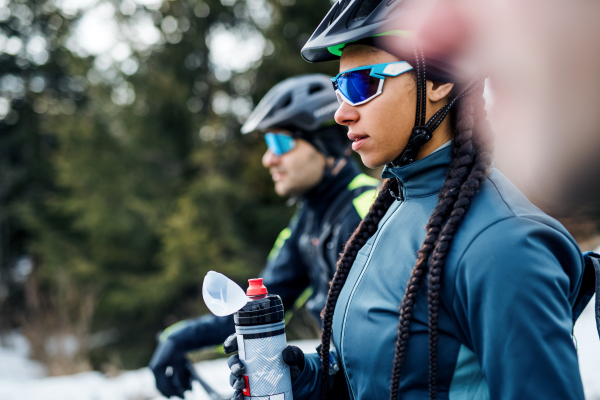 A group of young mountain bikers standing on road outdoors in winter.