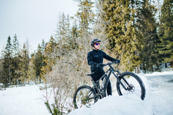 A male mountain biker riding in snow outdoors in winter nature.