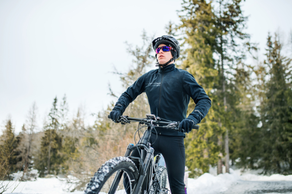 Front view of mountain biker with sunglasses standing outdoors in winter nature.