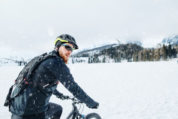 A side view of mountain biker riding in snow outdoors in winter nature.