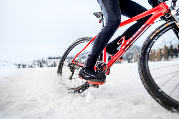 A midsection of mountain biker riding in snow outdoors in winter.