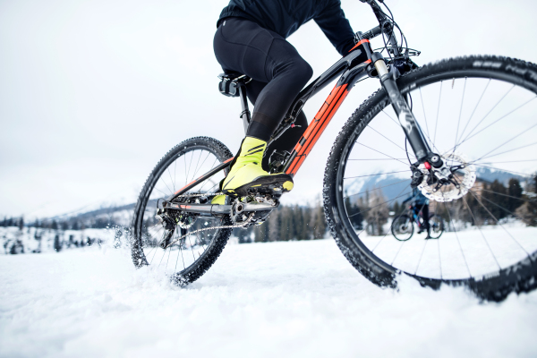 A midsection of mountain biker riding in snow outdoors in winter.