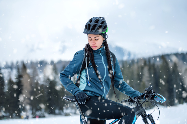 A happy female mountain biker standing outdoors in winter nature.