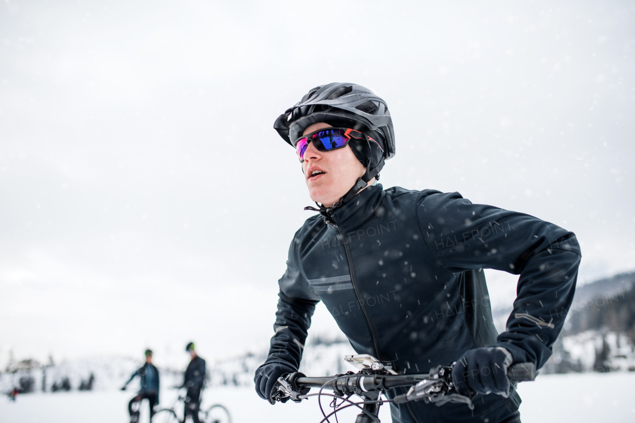 A side view of mountain biker riding in snow outdoors in winter nature.