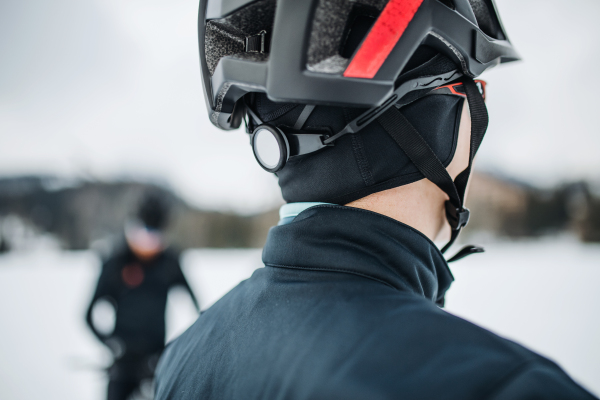 A rear view of mountain biker standing outdoors in winter, a close-up.