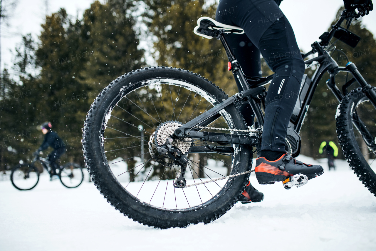 A midsection of mountain biker riding in snow outdoors in winter.