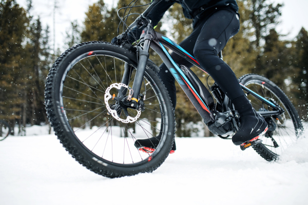 A midsection of mountain biker riding in snow outdoors in winter.