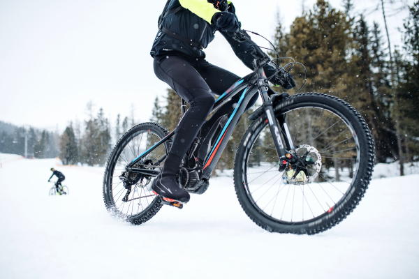 A midsection of mountain biker riding in snow outdoors in winter.