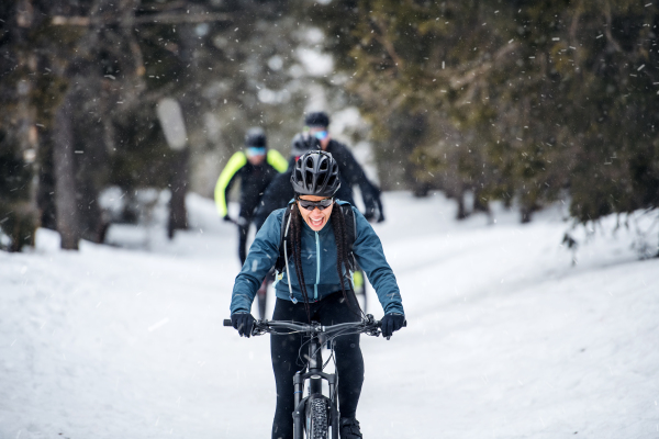 A group of young mountain bikers riding on road outdoors in winter.