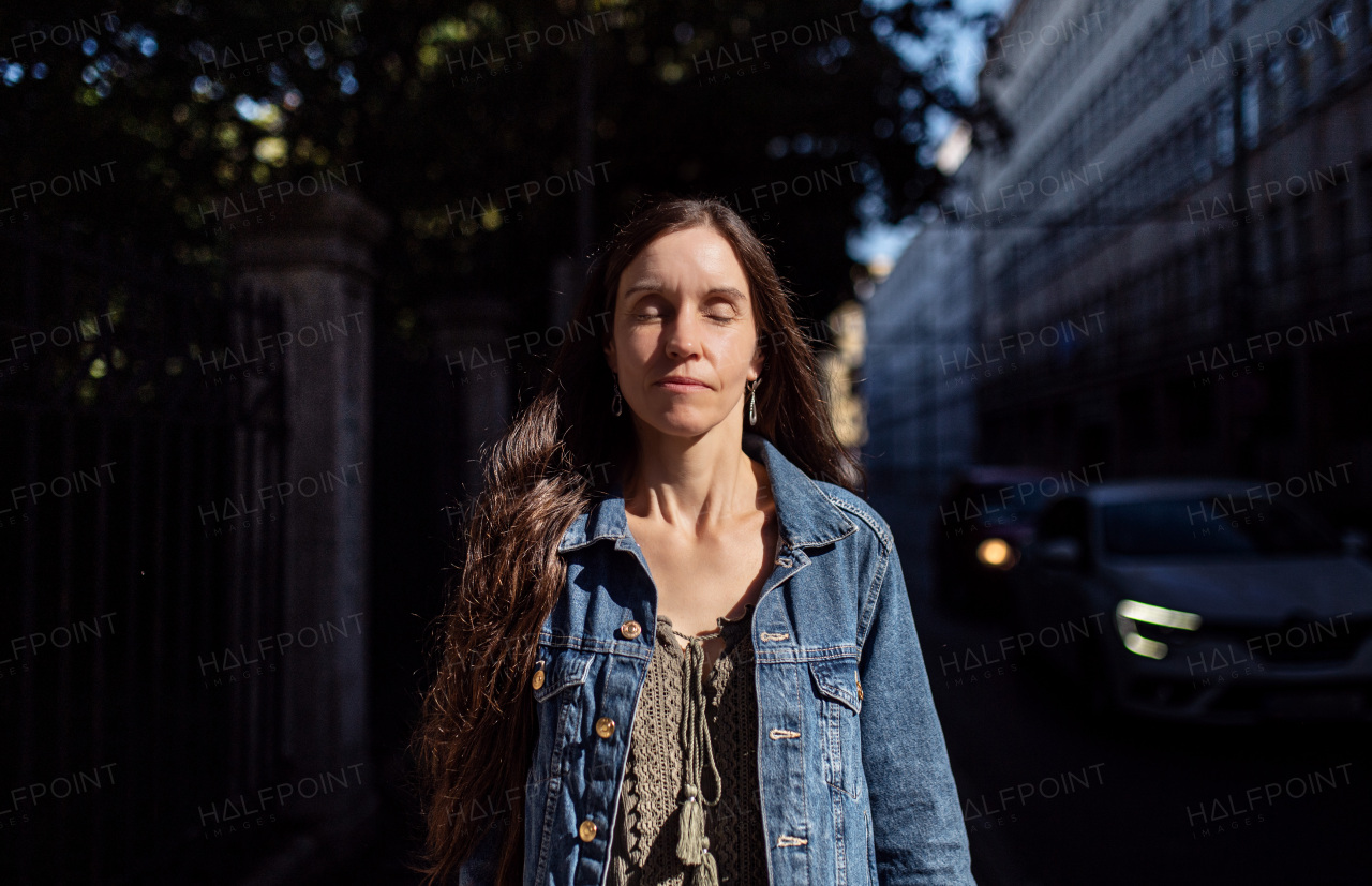 Portrait of mature woman standing outdoors in city or town park at dusk.