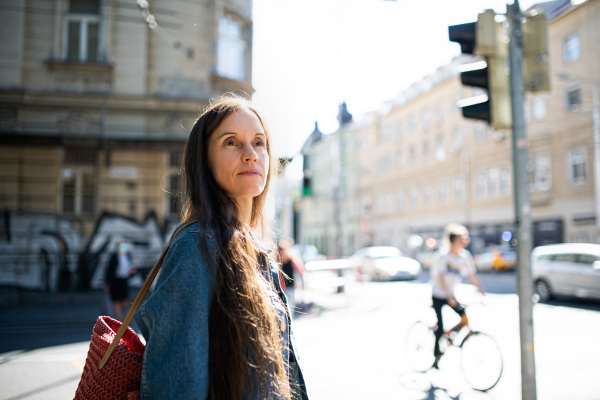 Portrait of mature woman walking outdoors in city or town park, crossing street.