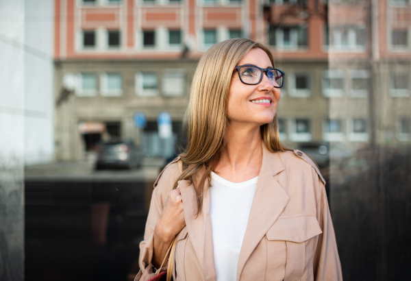 Portrait of happy senior woman standing outdoors in city or town.