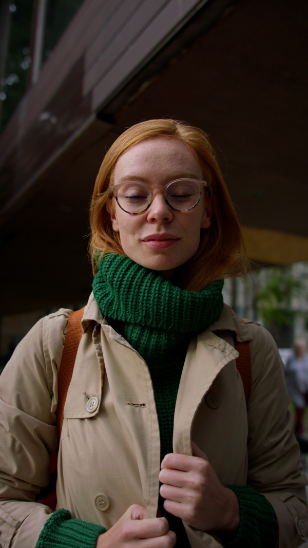 A veritcal footage of young woman turning and looking at camera in winter in street.