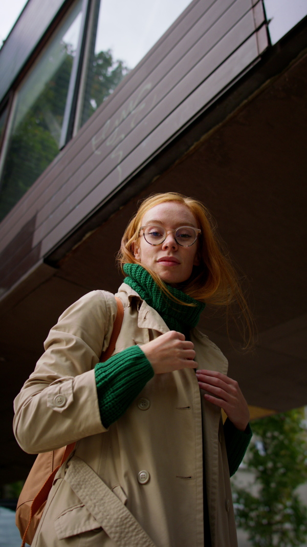 A veritcal footage of young woman turning and looking at camera in winter in street.