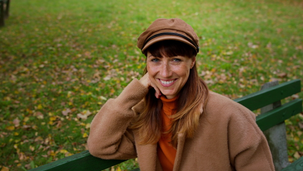 A beautiful mid adult woman looking at camera and smiling outdoors in park in autumn.