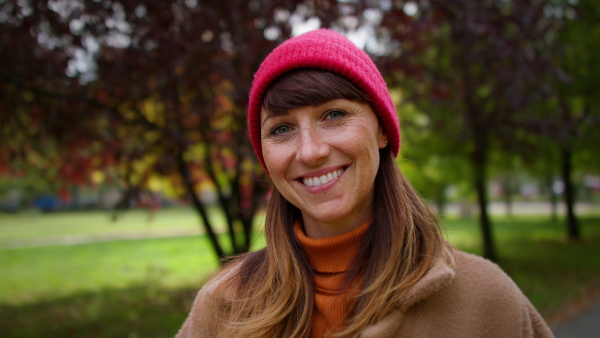 A beautiful mid adult woman looking at camera and smiling outdoors in park in autumn.