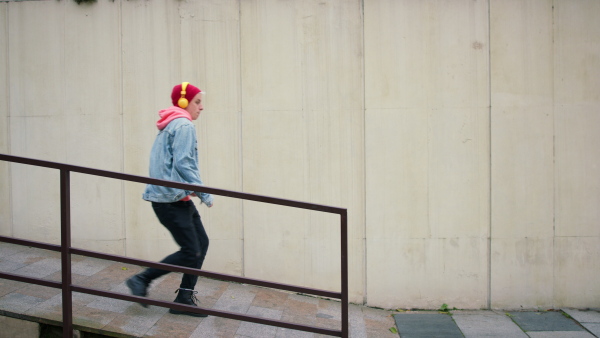 A cool young man with headphones jumping when running in street.