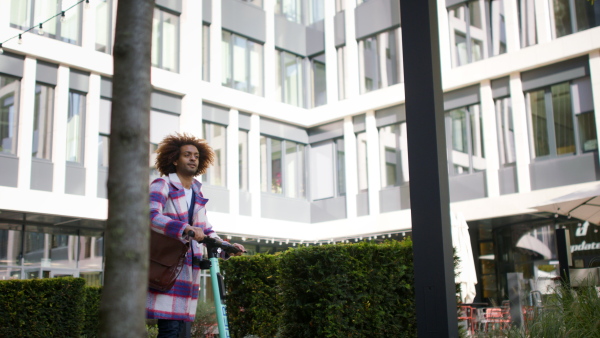 A cool multiracial mid audlt man riding electric scooter in street