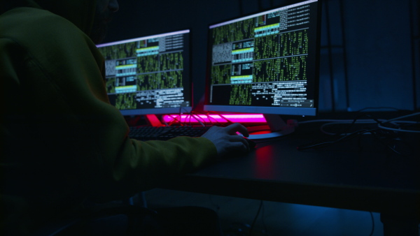 A young man hacker by computer in the dark room at night, cyberwar concept.