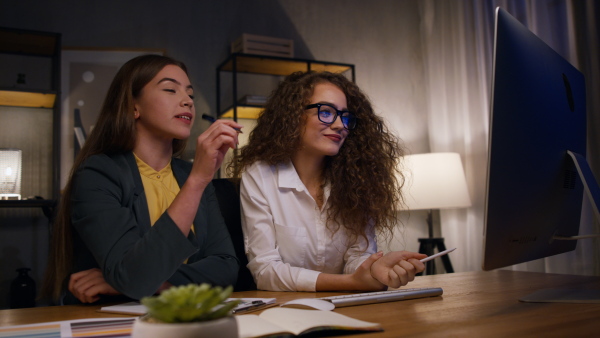 Young women, colleagues working together in an office during night.