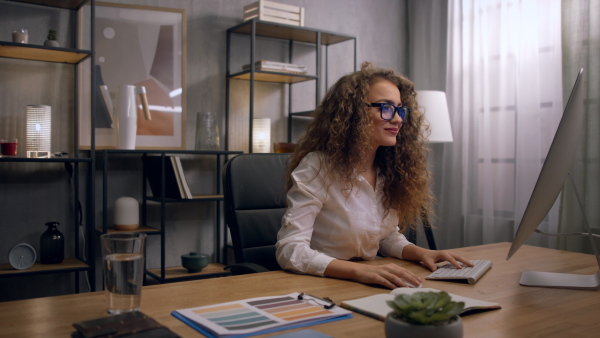 Close up of young woman working on computer in an office, looking at camera.