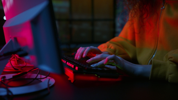 A young woman hacker by computer in the dark room at night, cyberwar concept.