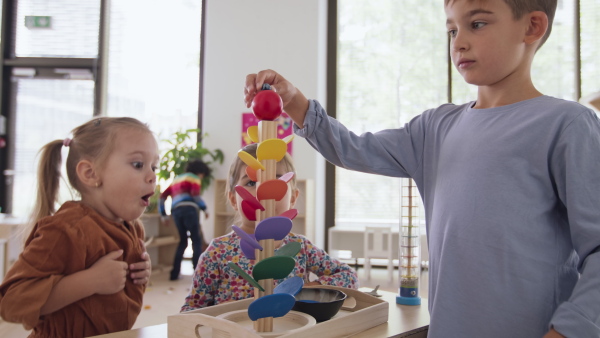 Children playing with a marble run indoors in nursery, montessori education.