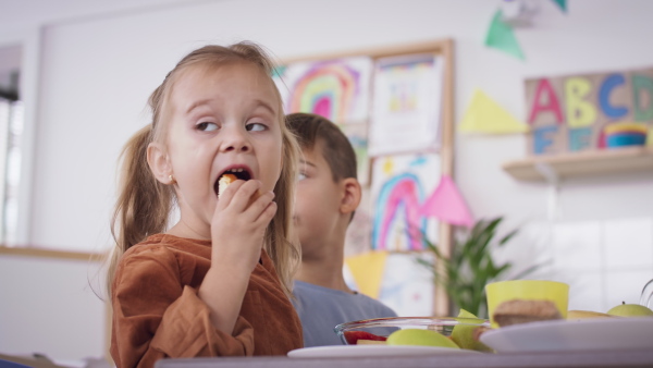 A pre school girl eating snack indoors at nursery school