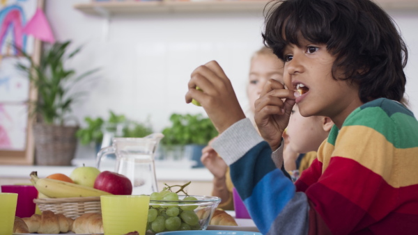 Pre school kids eating snack indoors at a nursery school