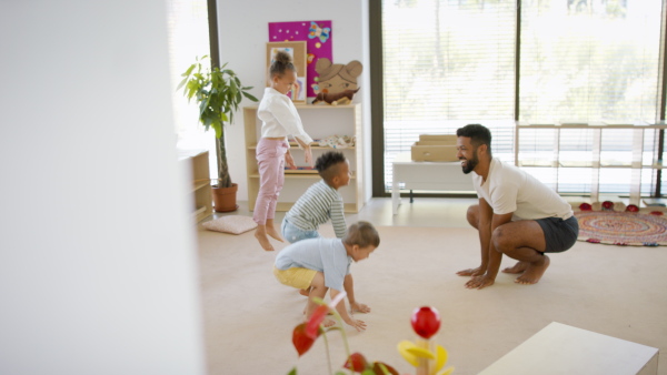 A group of small nursery school children with man teacher on floor indoors in classroom, doing exercise.