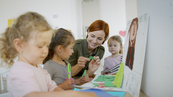 A group of small nursery school children with teacher indoors in classroom, art and craft concept.